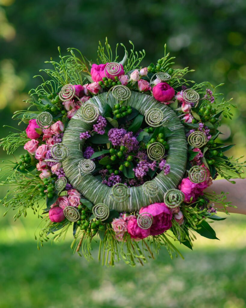 женщина держит букет розовых и зеленых цветов для Ляйсин Афониной.