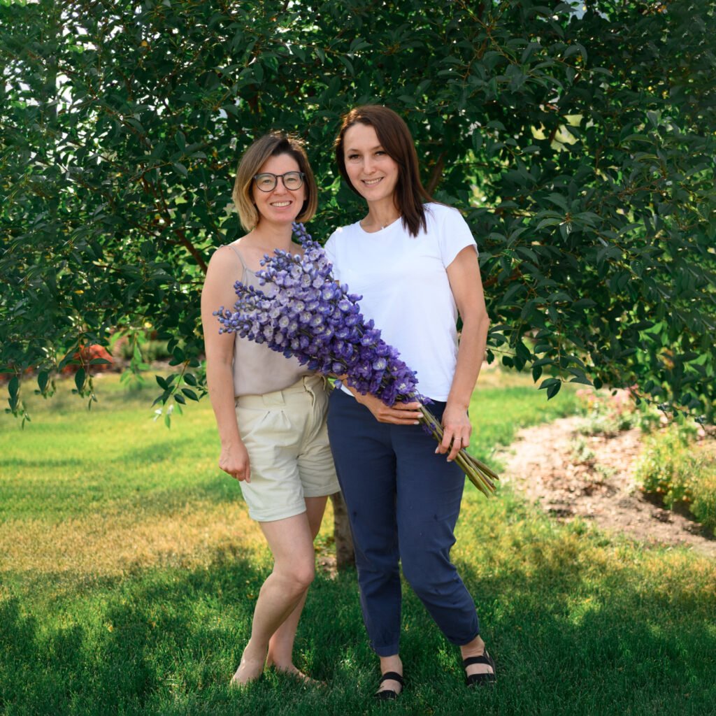 две женщины позируют перед деревом.